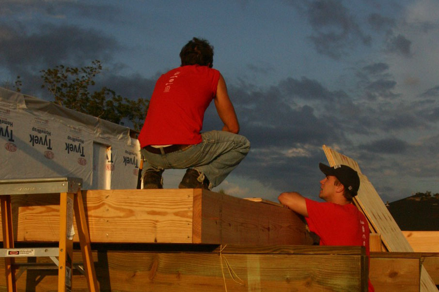 Workers sit on the roof of a home under construction