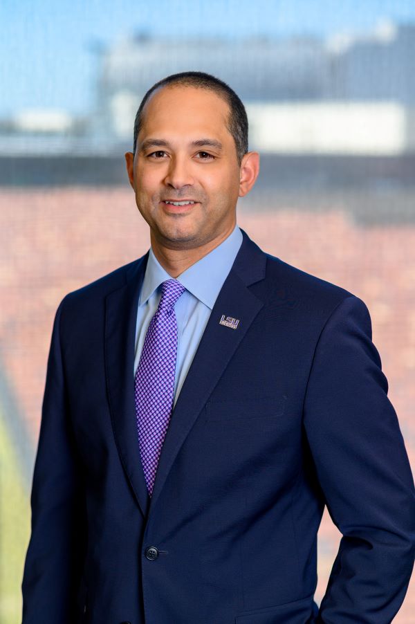 Jared Llorens in blue suit standing in front of a window.