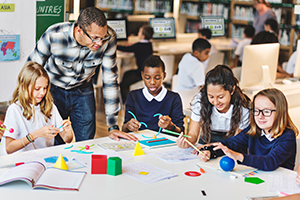 Photo of a teacher helping students with a geometry project.