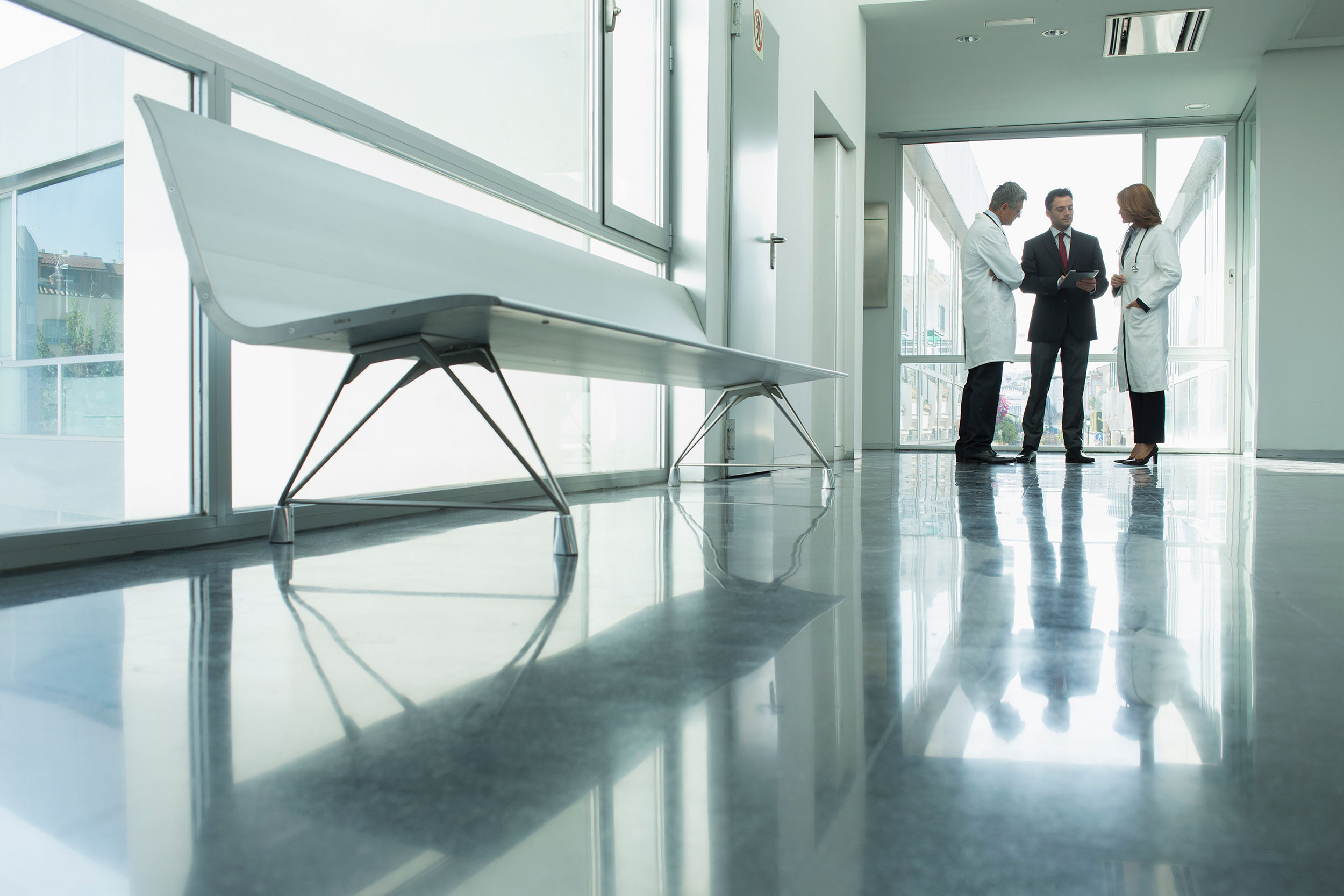 businessman talking to two doctors in a hospital hallway