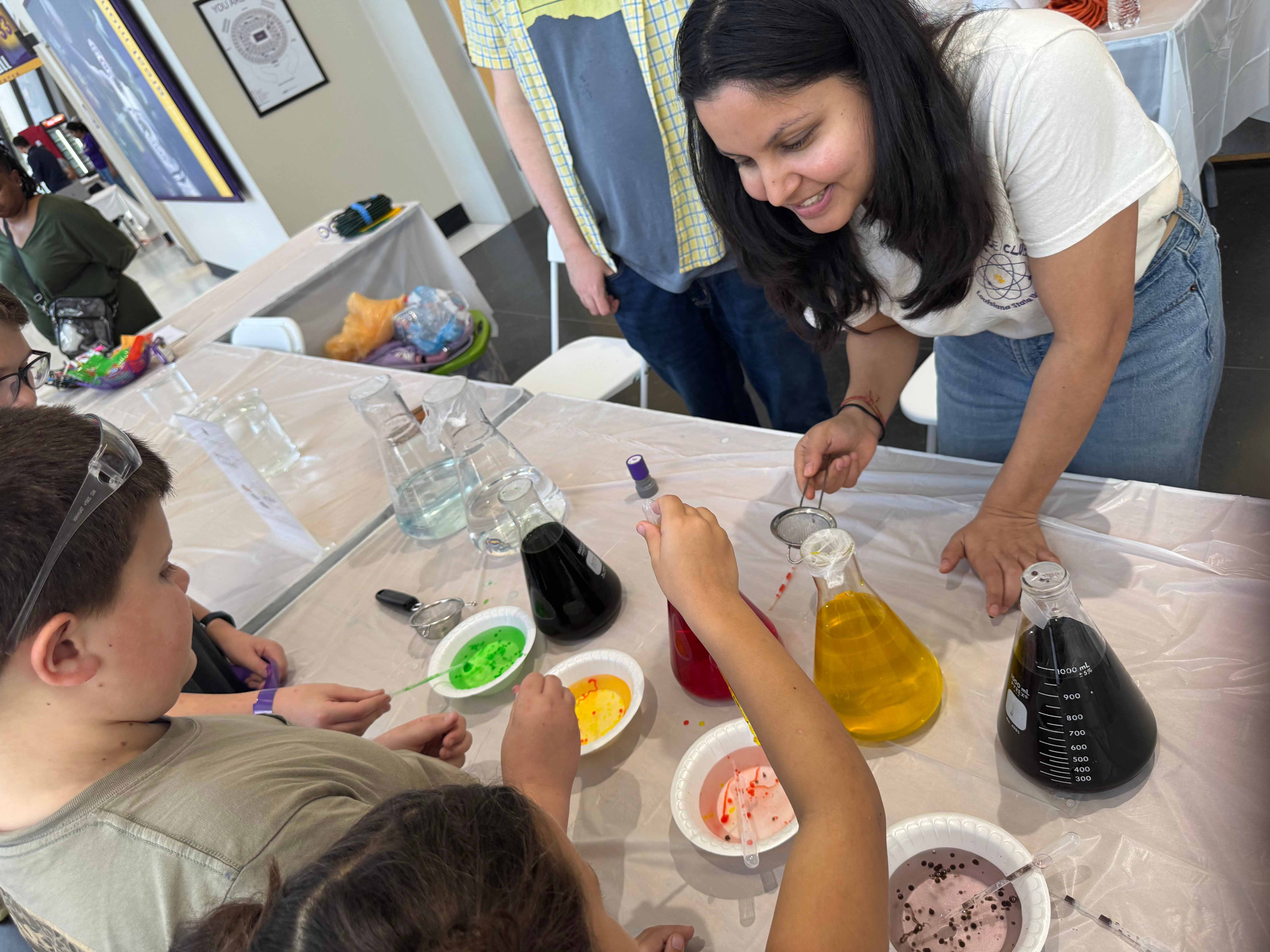 woman showing kids containers with colored water